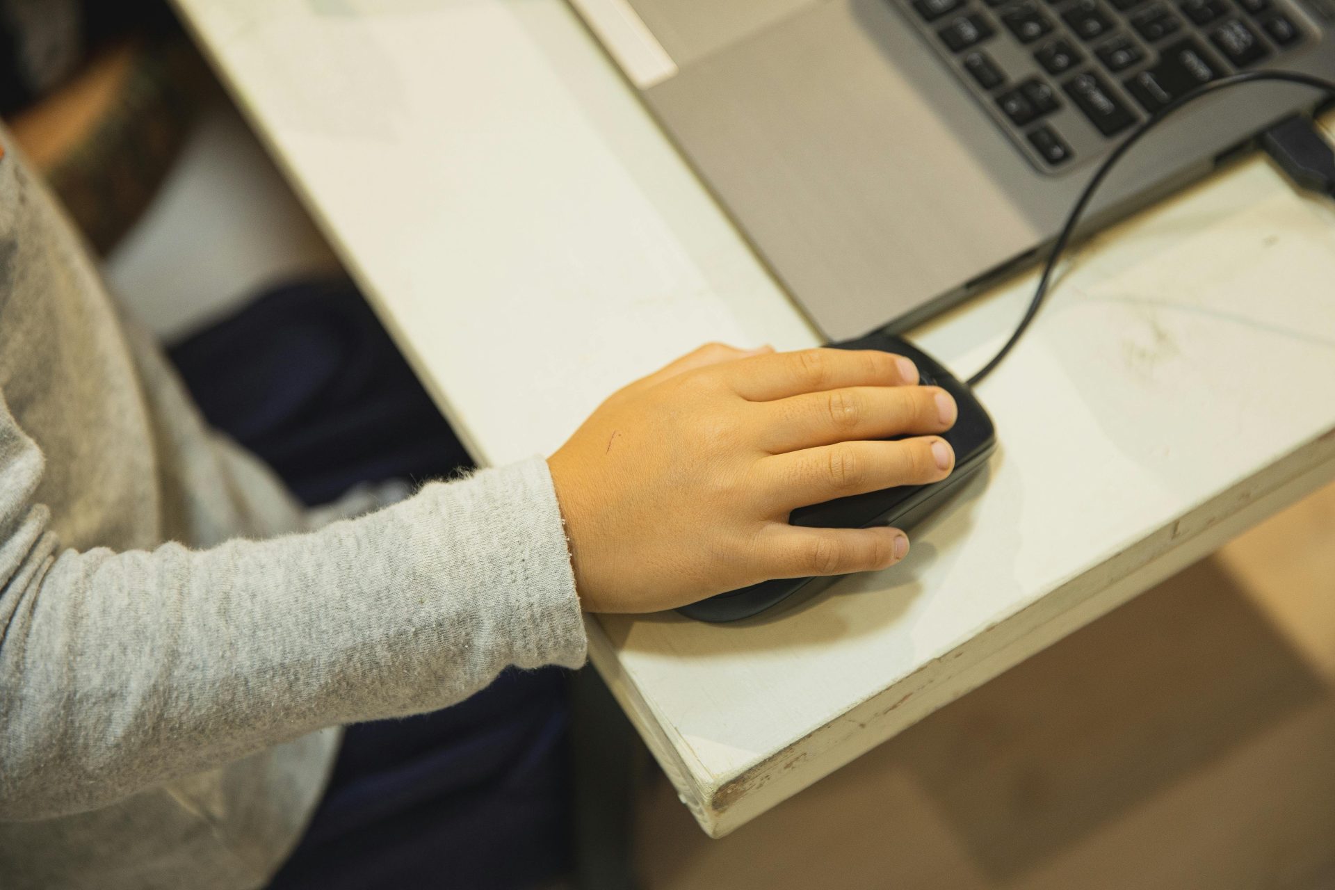 Von oben: Anonymer Schüler benutzt die Maus seines Netbooks im Computerunterricht in der Schule (Bildausschnitt).