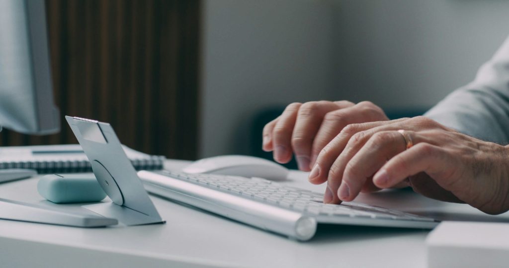 Eine Person, die an einem Schreibtisch auf einer Tastatur tippt.