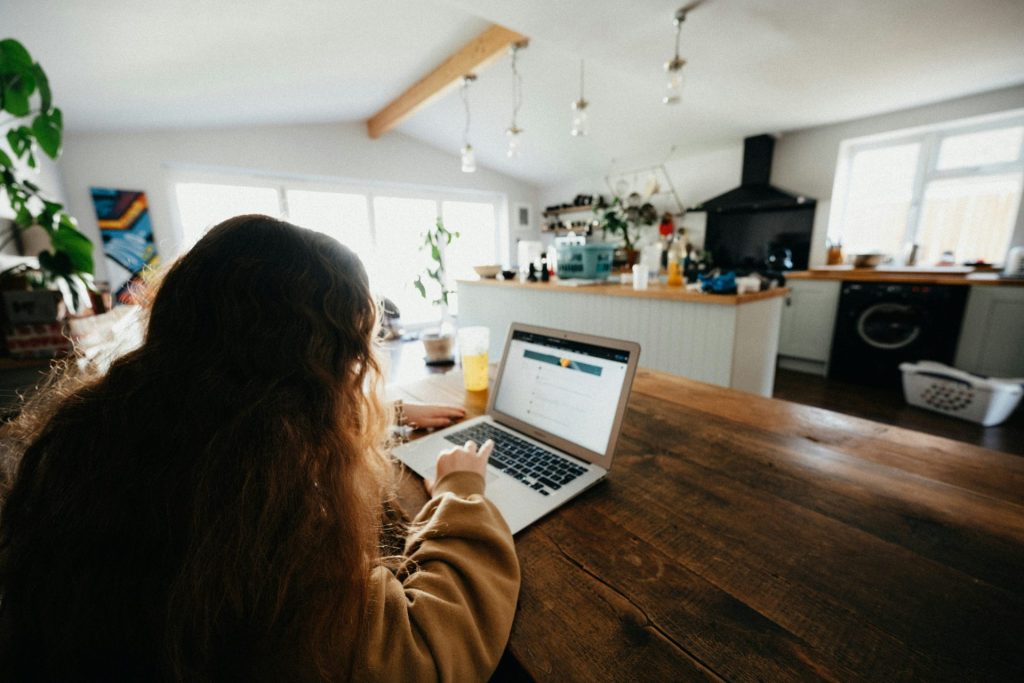 Frau im braunen Pullover benutzt ein MacBook Pro